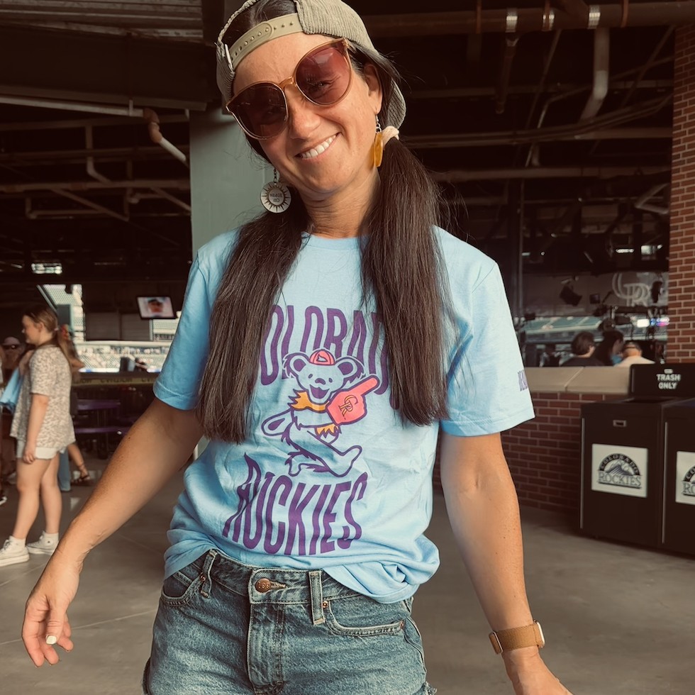 Dr. Catie Shonts smiling at a Colorado Rockies game, wearing a Grateful Dead-themed Rockies t-shirt